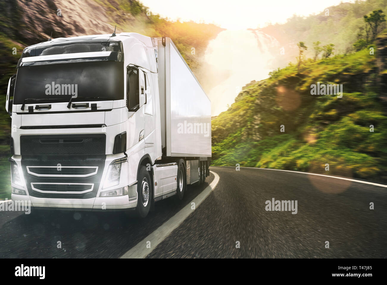 White truck moving on the road in a natural landscape at sunset Stock Photo