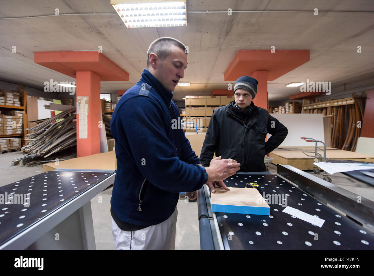 two young carpenters calculating and programming a cnc wood working machine in workshop. wood workers preparing a computer program for CNC machine at  Stock Photo