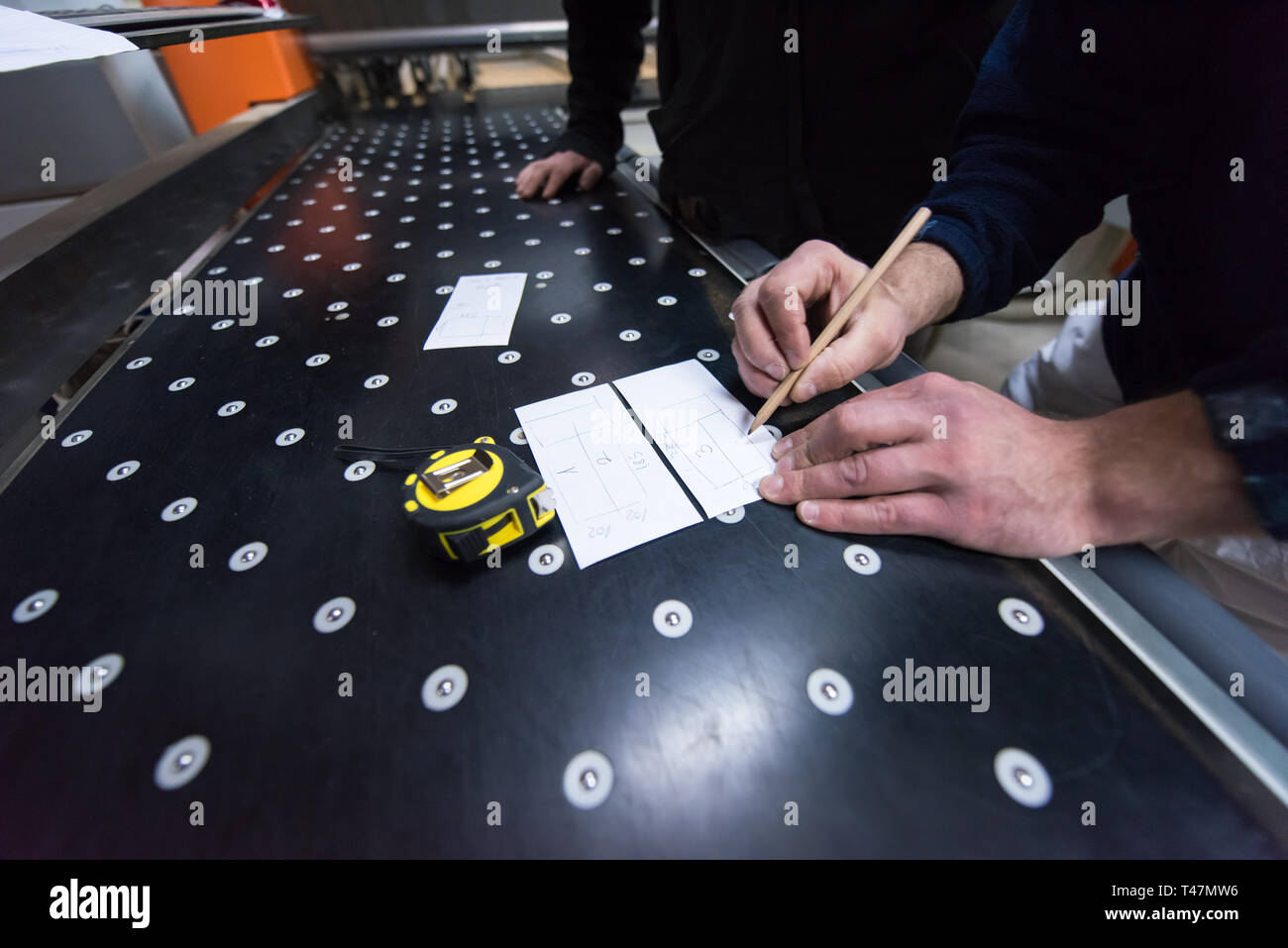 two young carpenters calculating and programming a cnc wood working machine in workshop. wood workers preparing a computer program for CNC machine at  Stock Photo