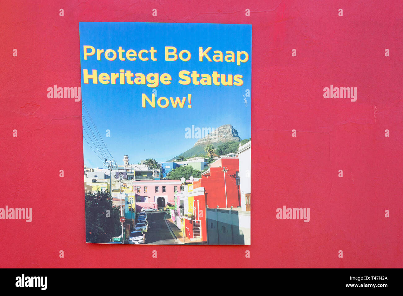 poster on red wall with words protect Bo Kaap Heritage status now as a protest against further development of land in the area for commercial purposes Stock Photo