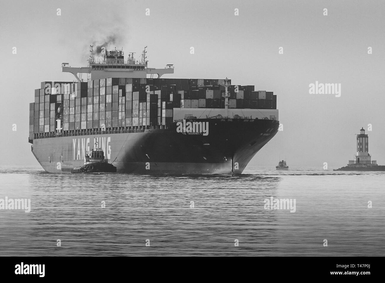 Black And White Photo Of The YANG MING Container Ship, YM UNANIMITY, Entering The Los Angeles Main Channel, The Angels Gate Lighthouse To The Right. Stock Photo