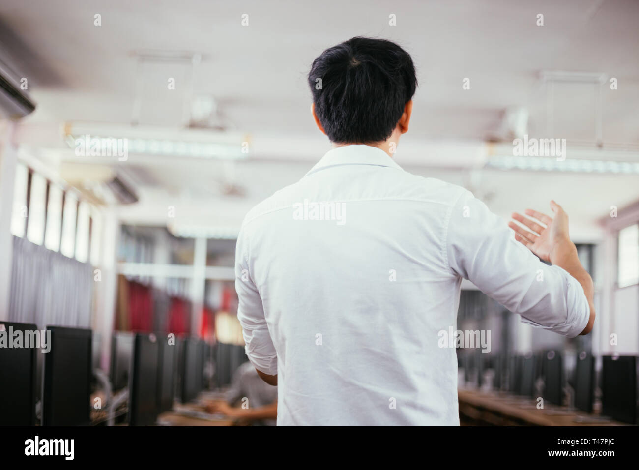 Rear view of male businessman speaking and making a lecture in public ...