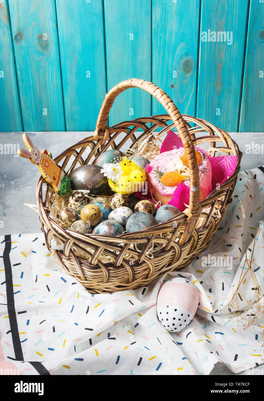 Basket with easter cakes and painted eggs on concrete background. Easter concept Stock Photo