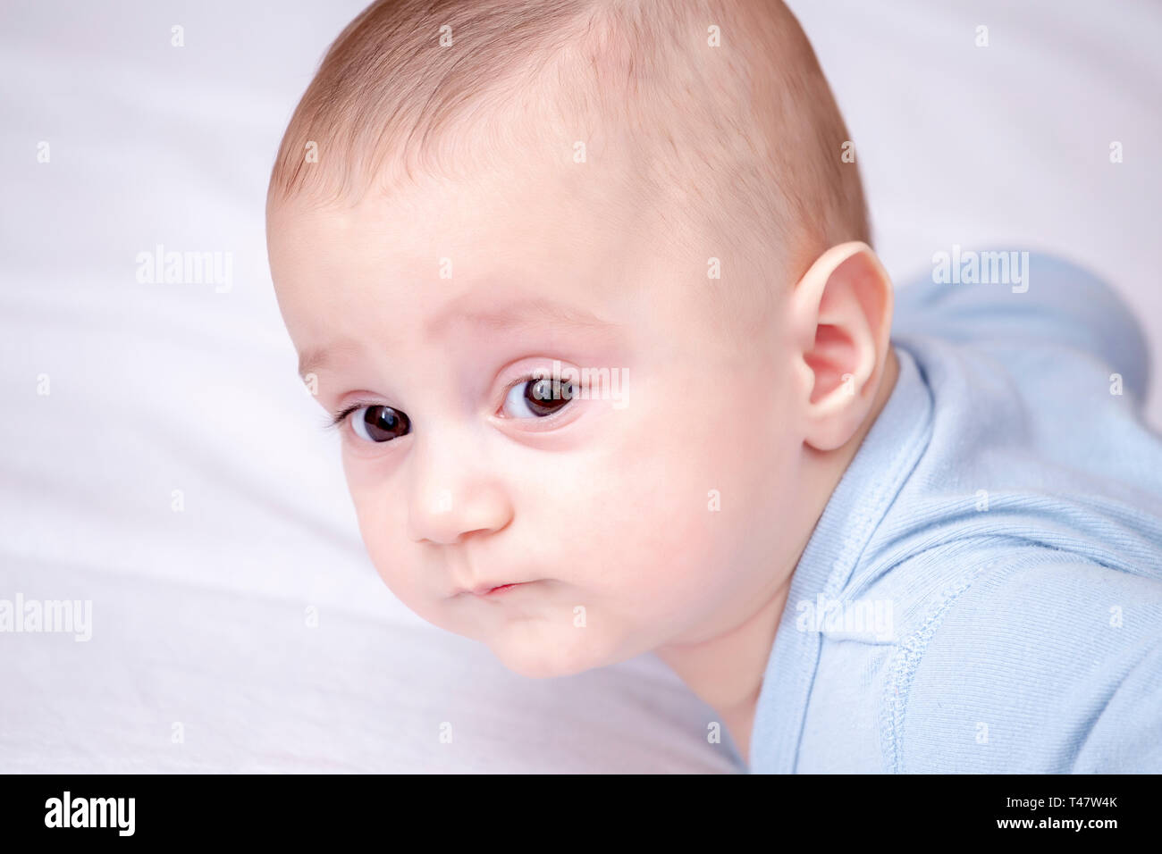 Portret of baby boy laying on his stomach side view. Abstract: When to start tummy time. Stock Photo