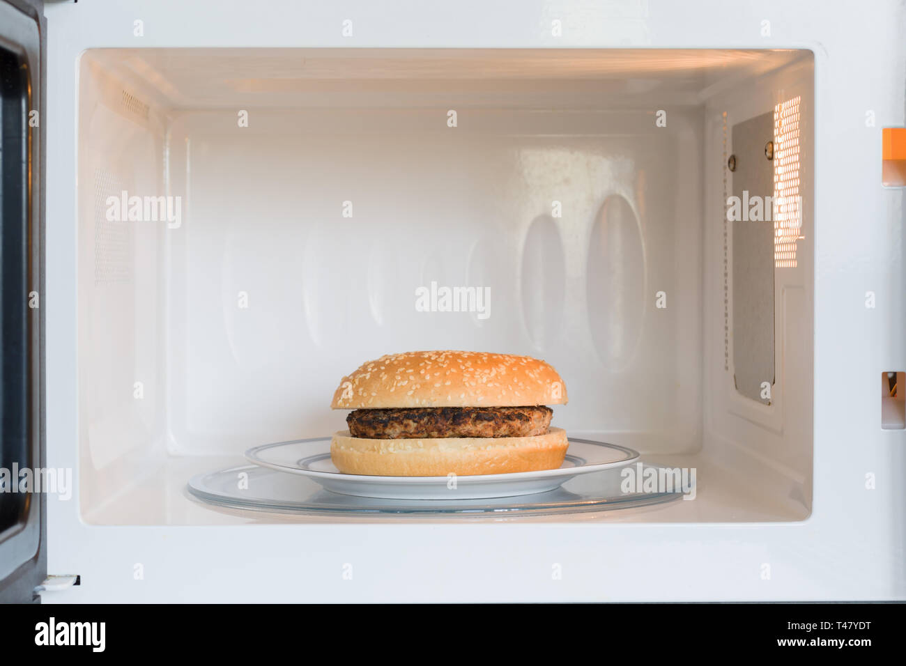 Unappealing microwavable hamburger on a plate in a microwave oven Stock Photo