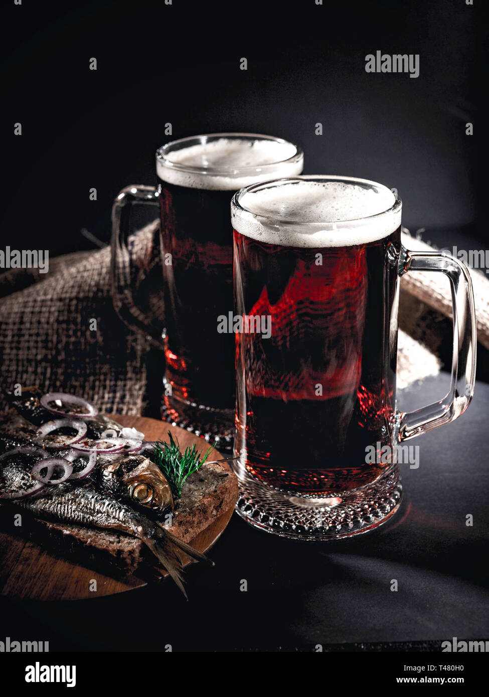 Red craft beer, hot smoked fish sandwich on a dark background. Low key lighting. Vertical shot Stock Photo