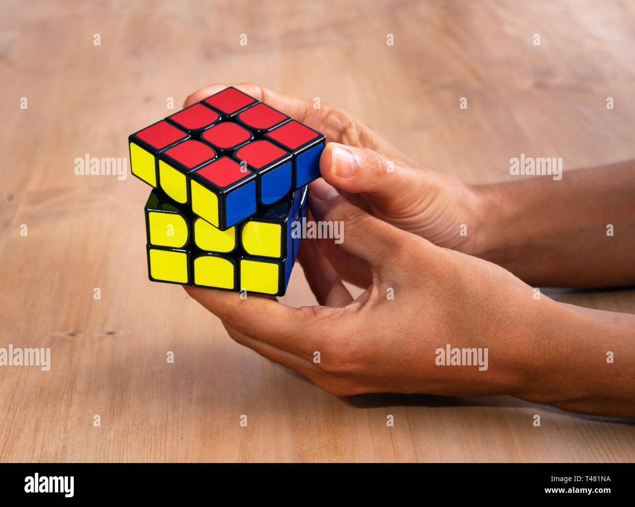 Rubik cube intelligence toy solving in a hand, in a wood table Stock Photo