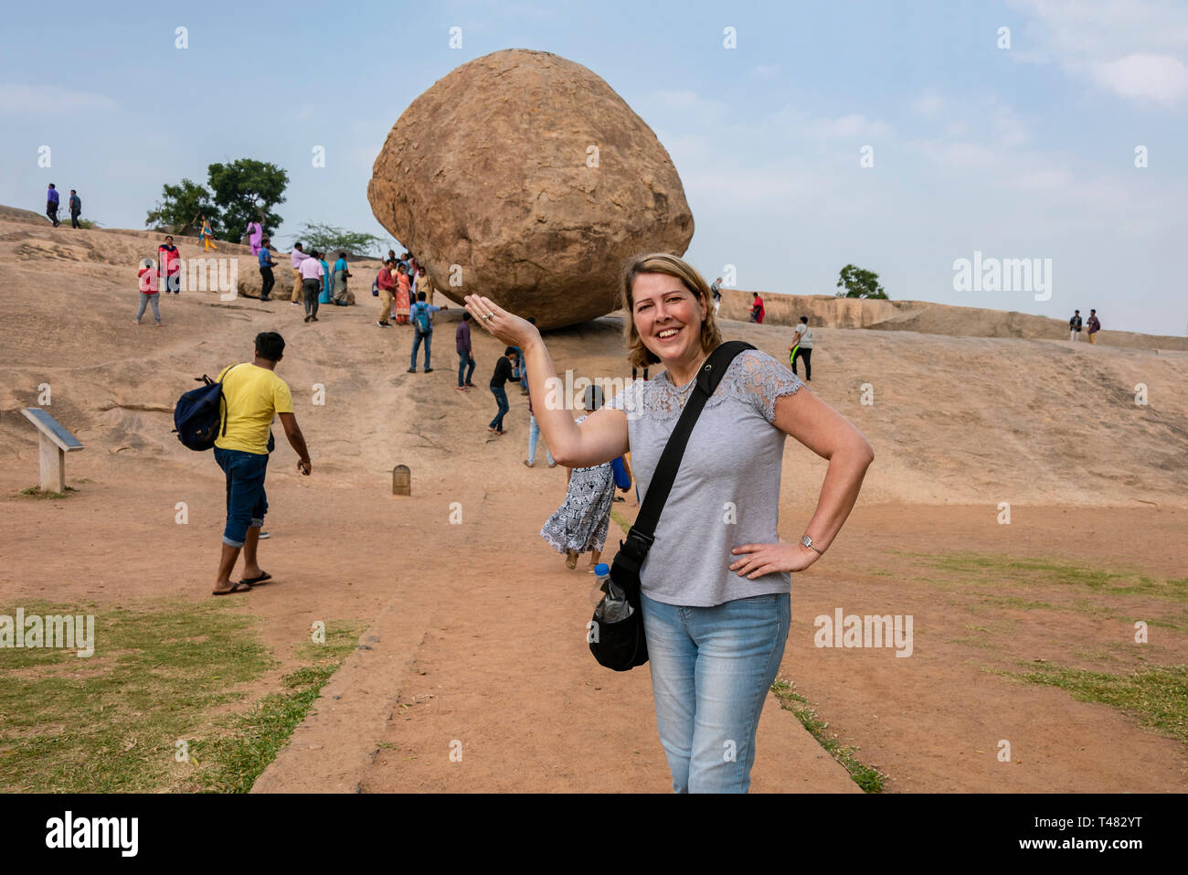 Horizontal portrait of a tourist pretending to hold Krishna's Butterball at Mahabalipuram, India. Stock Photo