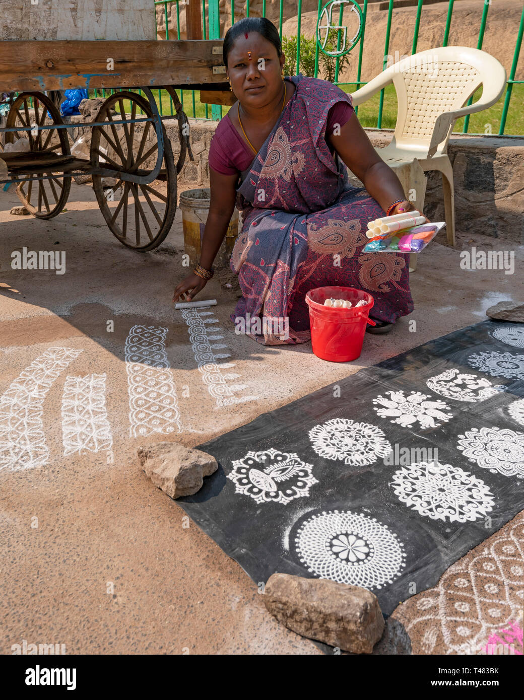 Vertical view of a lady making rangoli patterns on the roadside in India. Stock Photo