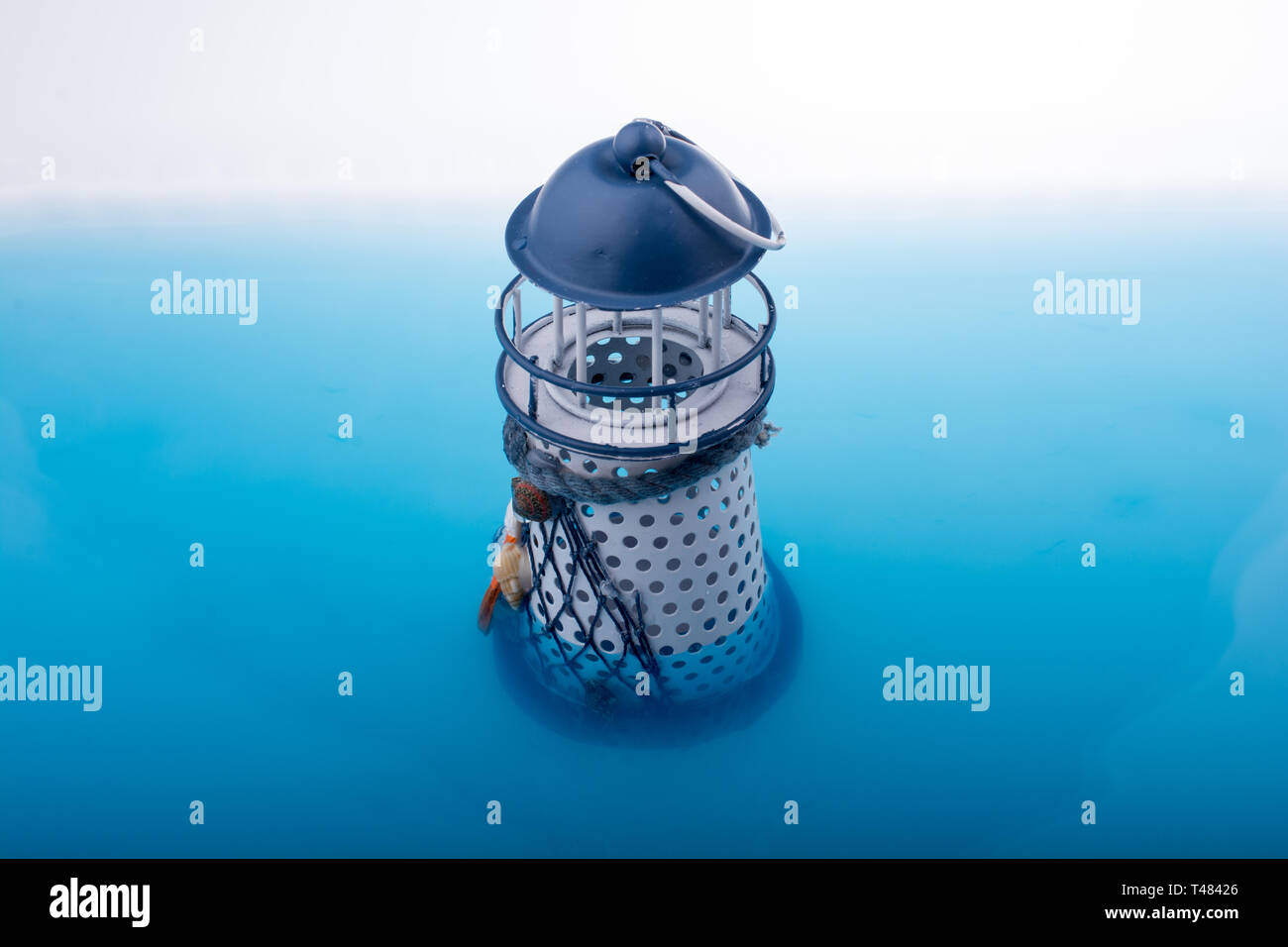 Little model lighthouse placed in blue water Stock Photo - Alamy