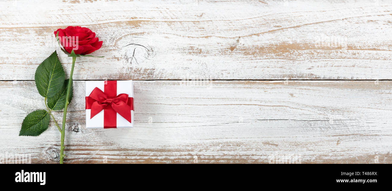 Anniversary background with a single red rose and wrapped gift box on ...
