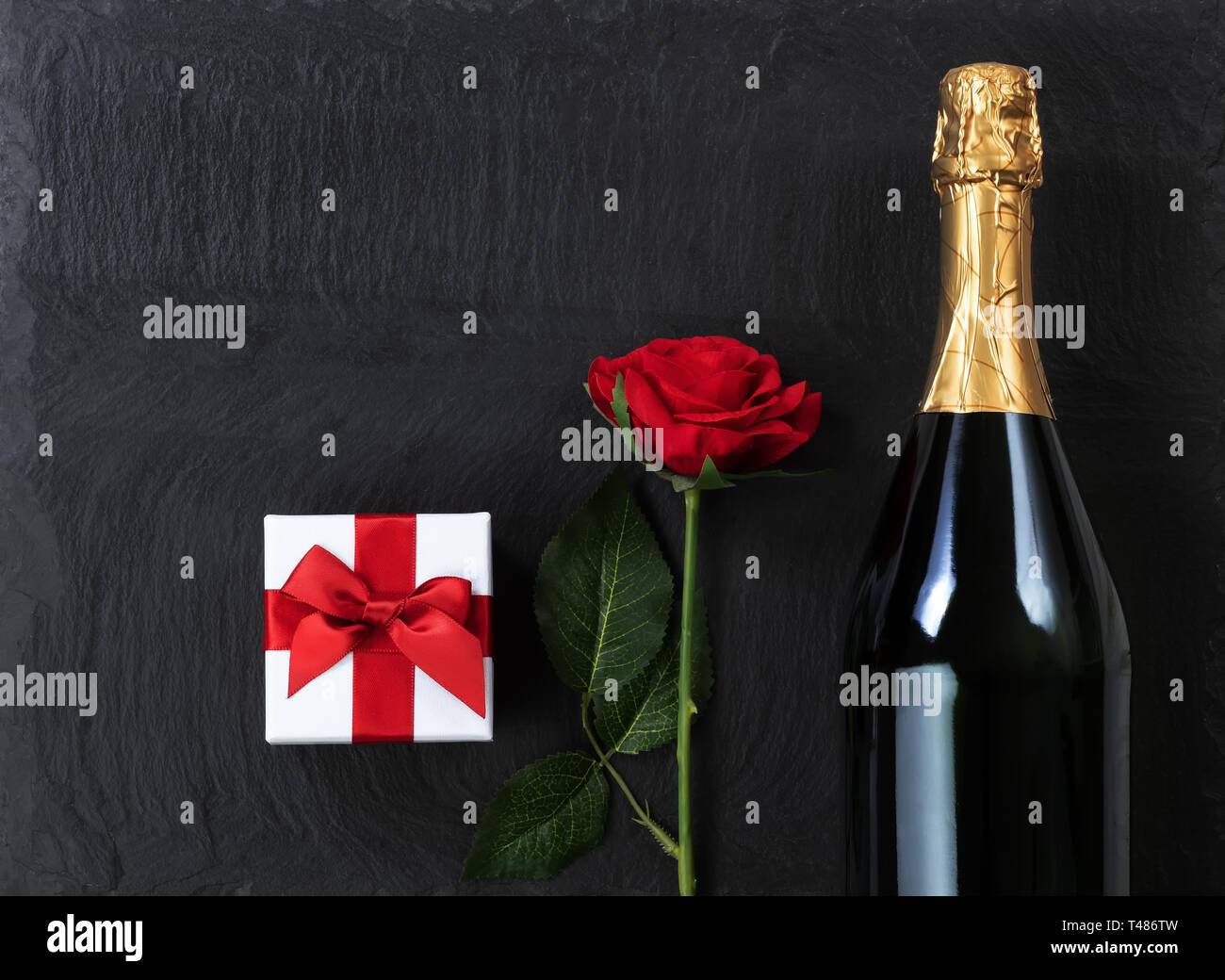 Anniversary background with champagne and gifts on natural black slate stone Stock Photo