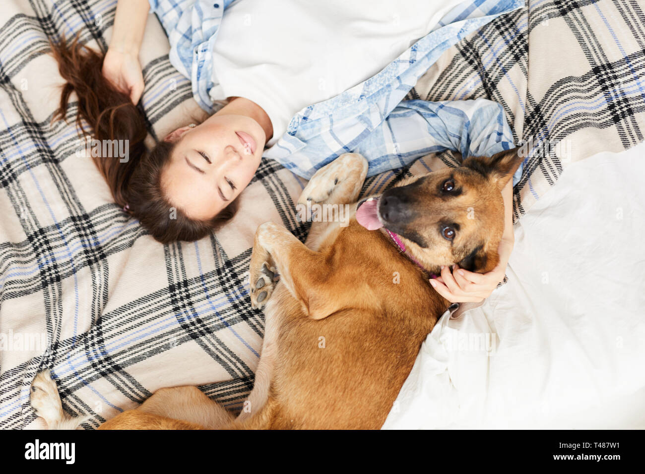 Asian Woman Lying on Bed with Dog Stock Photo
