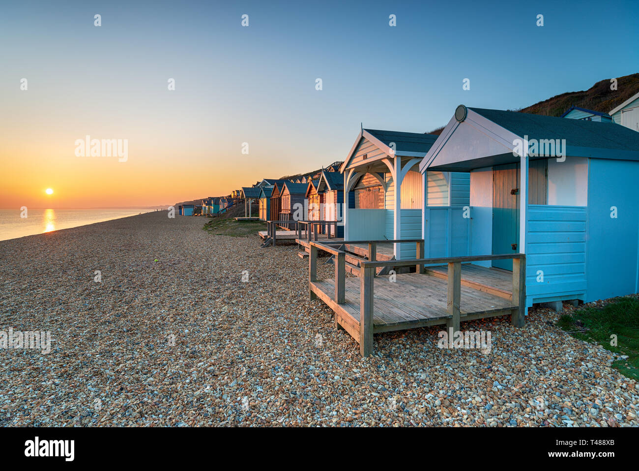 Beautiful sunset over a row of colourful beach huts at Milford on Sea on the Hampshire coast Stock Photo