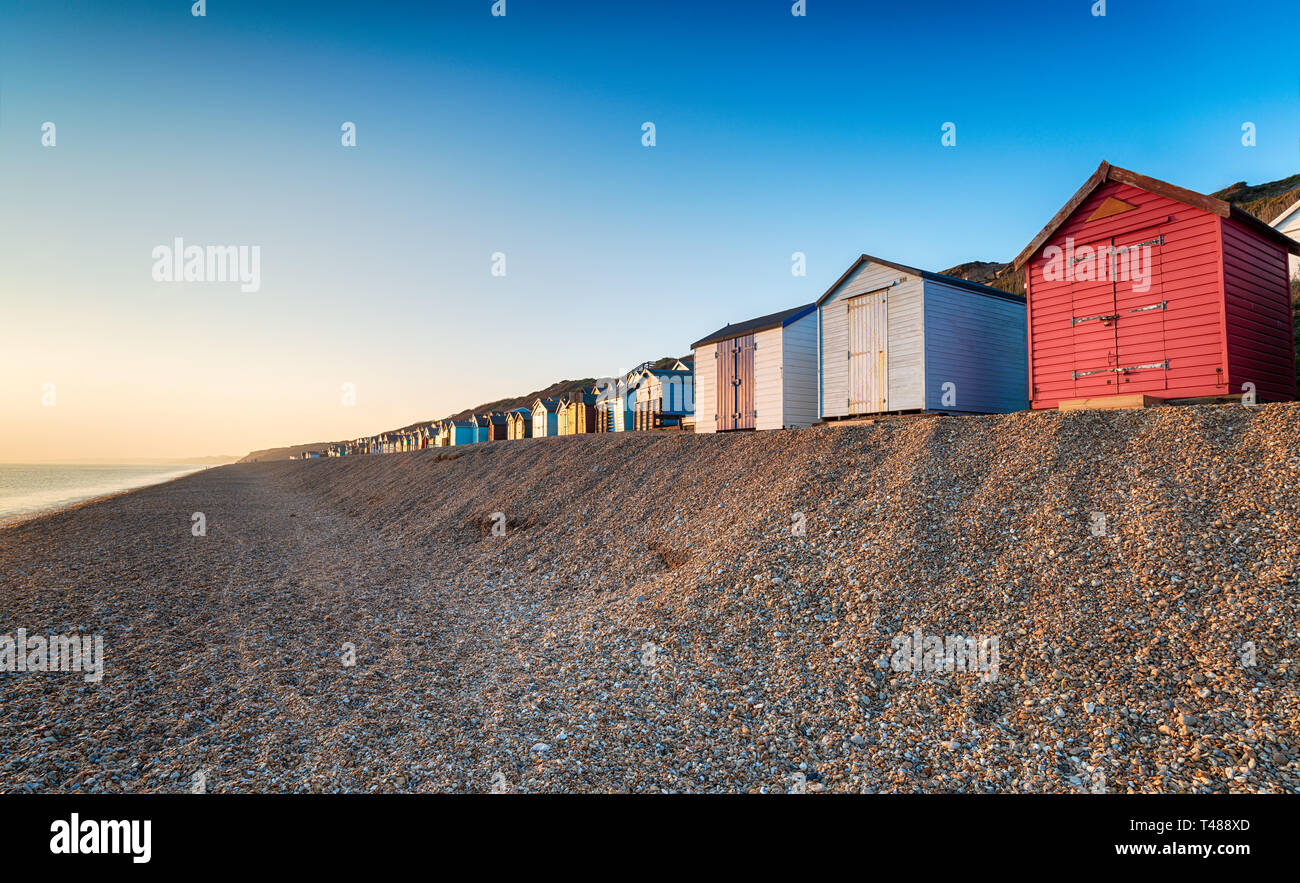 A row of colourful beach huts on a shingle beach at Milford on Sea on the Hampshire coast Stock Photo