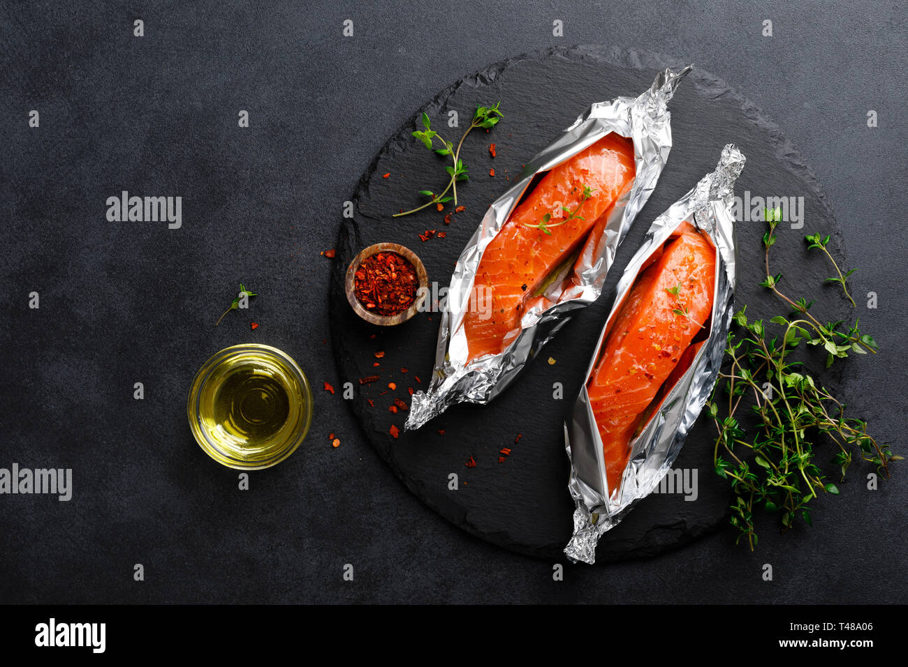 Raw salmon fish fillet in foil on black background Stock Photo - Alamy
