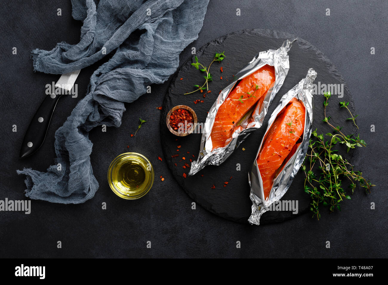 Raw salmon fish fillet in foil on black background Stock Photo - Alamy