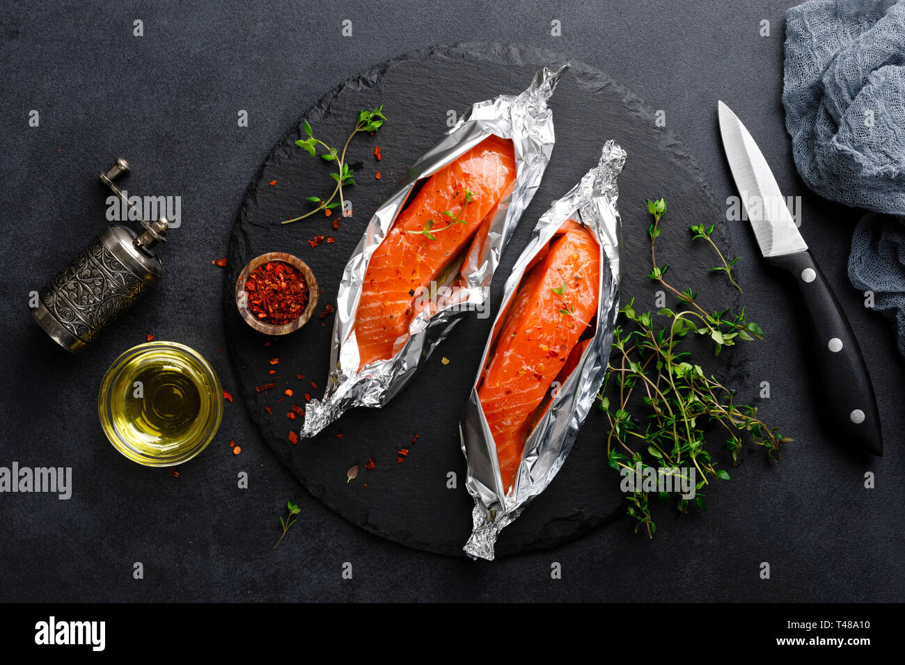 Raw salmon fish fillet in foil on black background Stock Photo - Alamy