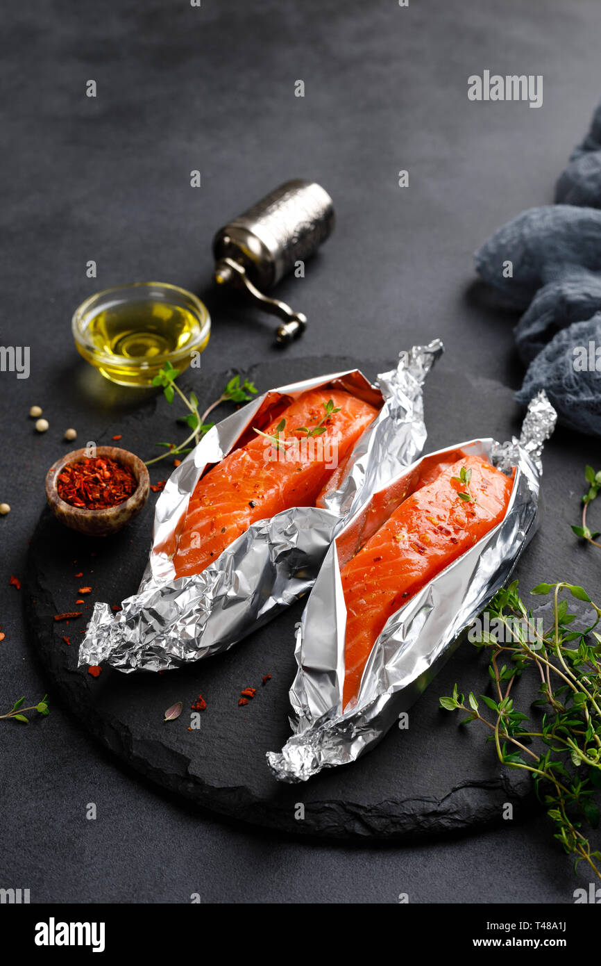 Raw salmon fish fillet in foil on black background Stock Photo - Alamy
