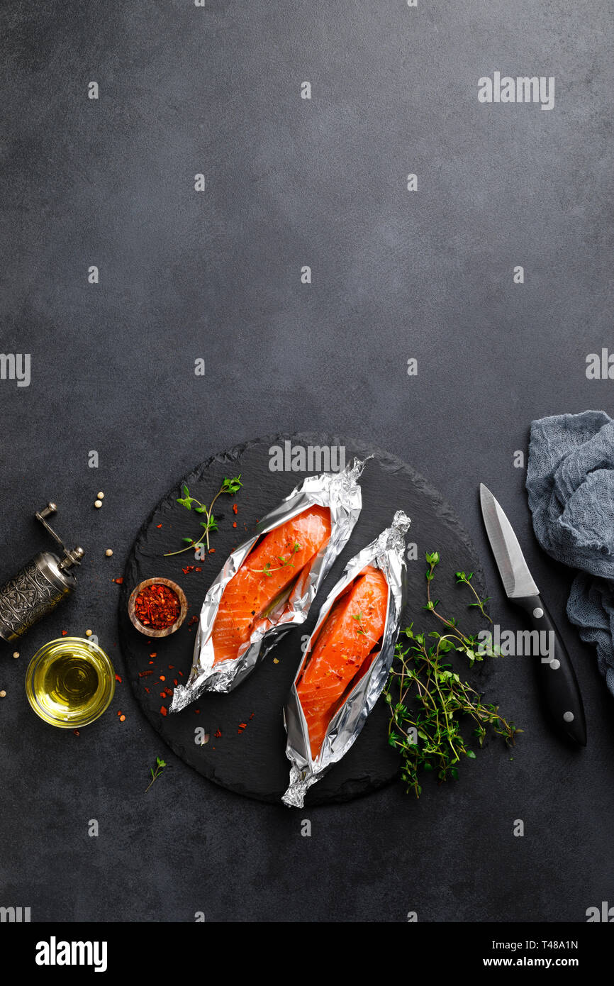 Raw salmon fish fillet in foil on black background Stock Photo - Alamy