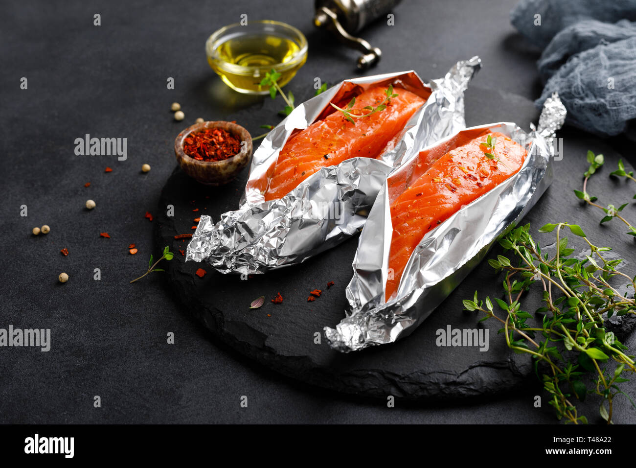 Raw salmon fish fillet in foil on black background Stock Photo - Alamy