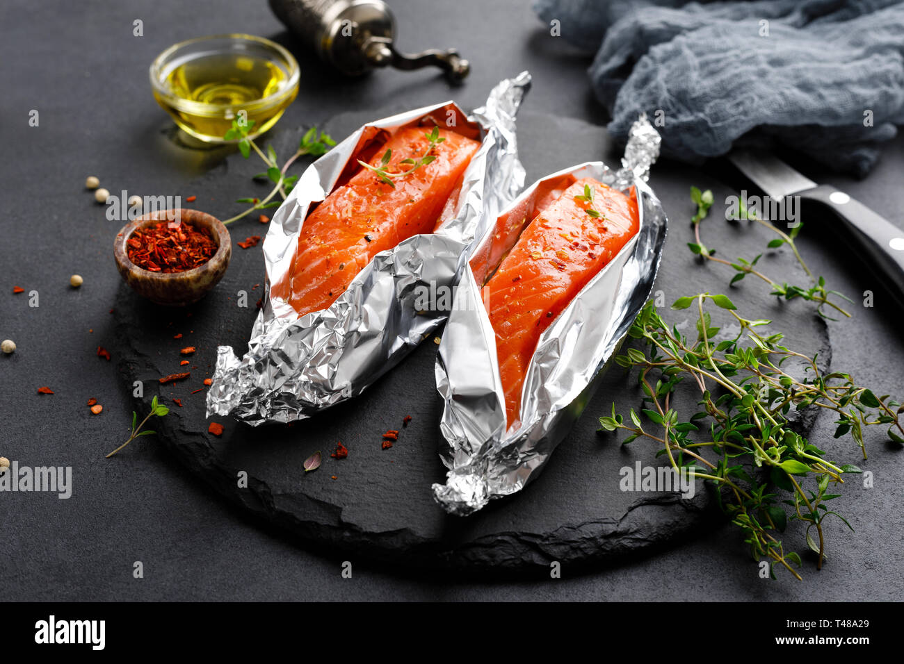 Raw salmon fish fillet in foil on black background Stock Photo - Alamy