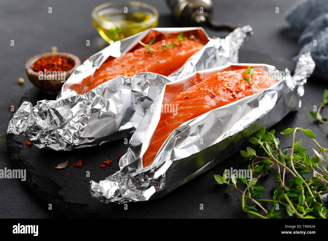 Raw salmon fish fillet in foil on black background Stock Photo - Alamy