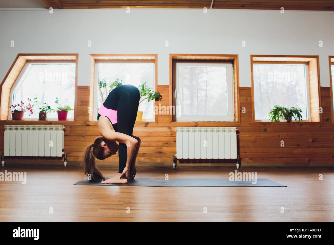 An unidentified young woman doing an exercise of yoga Padahastasana