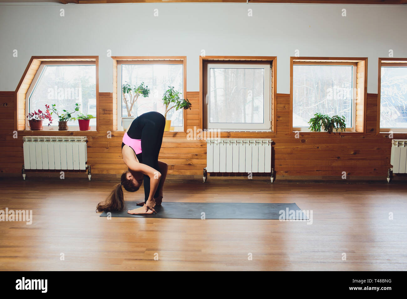 Padahastasana. Beautiful yoga woman practice in a training hall background. Yoga concept. Stock Photo