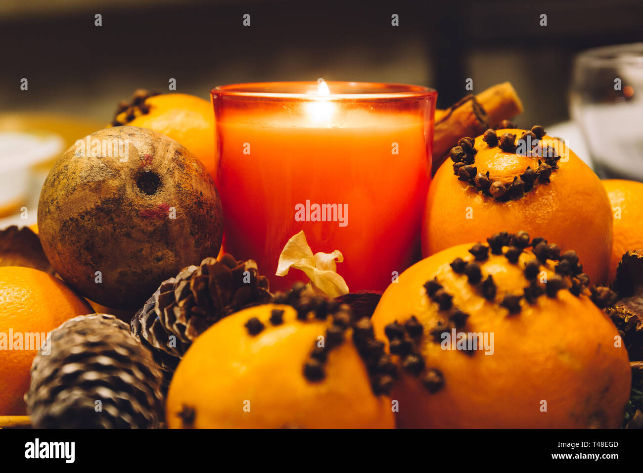 Christmas decoration candle set, with pine cones and oranges decorated with cloves, on a dinner table. Stock Photo