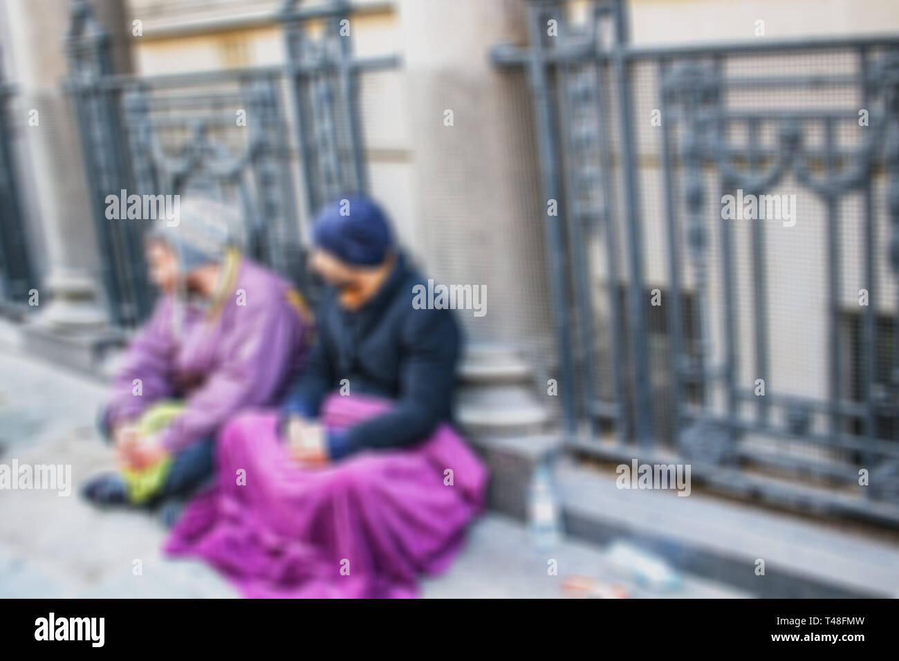 Blurred unidentified homeless men begging on city street. Stock Photo