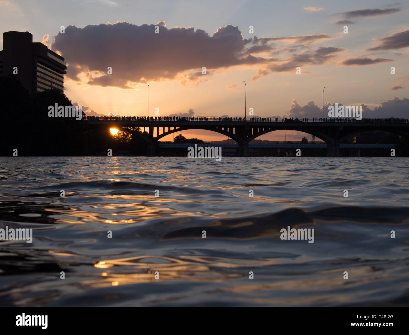 As the sun sets, hundreds of onlookers wait on bats to emerge from the Congress Avenue bridge in Austin, Texas Stock Photo
