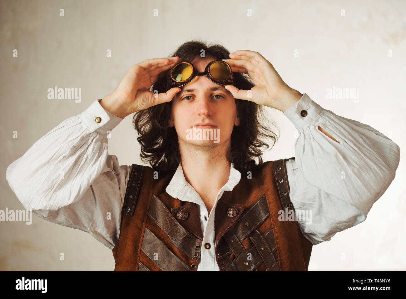 Steampunk pilot in a leather vest and flight glasses on his forehead.  Vintage style man looking up Stock Photo - Alamy