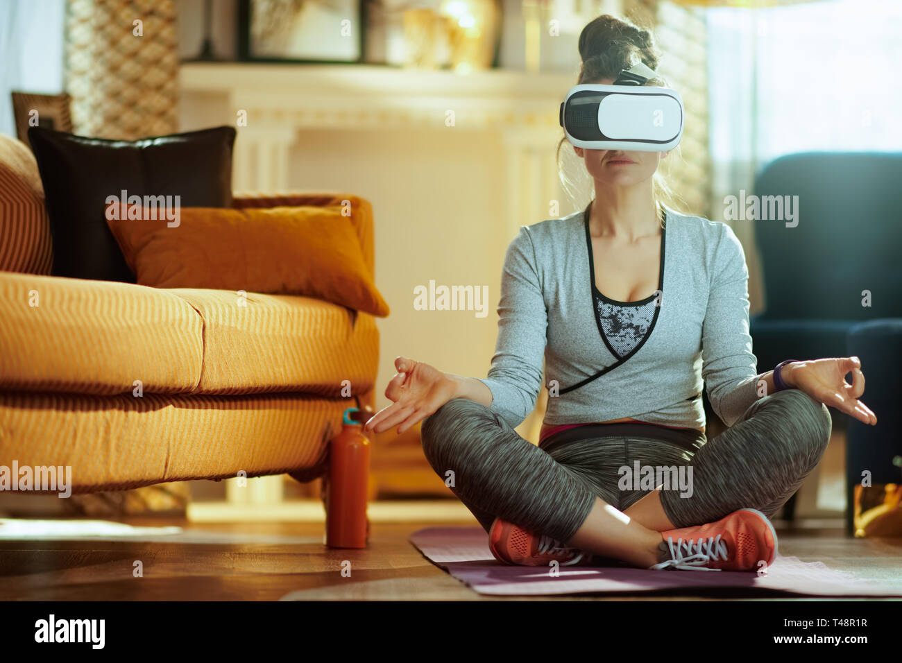 relaxed fit woman in sport clothes in the modern house in VR gear Stock