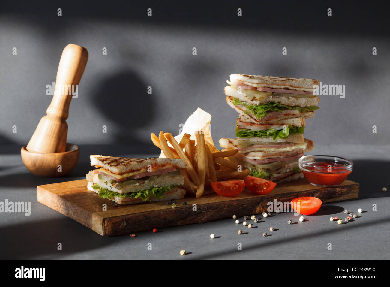 Photo session new menu of coffee house, fresh club sandwich with chicken  and vegetables, lettuce salad, french fries and ketchup on wooden desk on  bla Stock Photo - Alamy