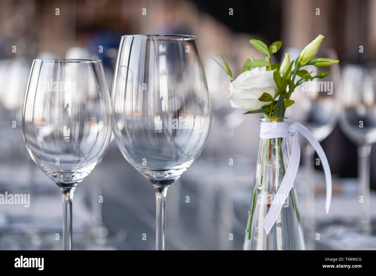 Modern restaurant setting, glass vase with bouquet flowers on table in