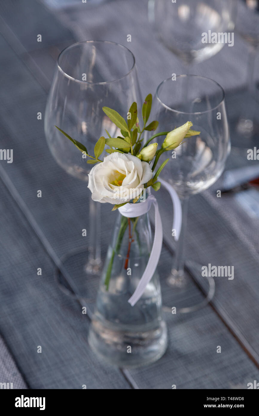 Modern restaurant setting, glass vase with bouquet flowers on table in