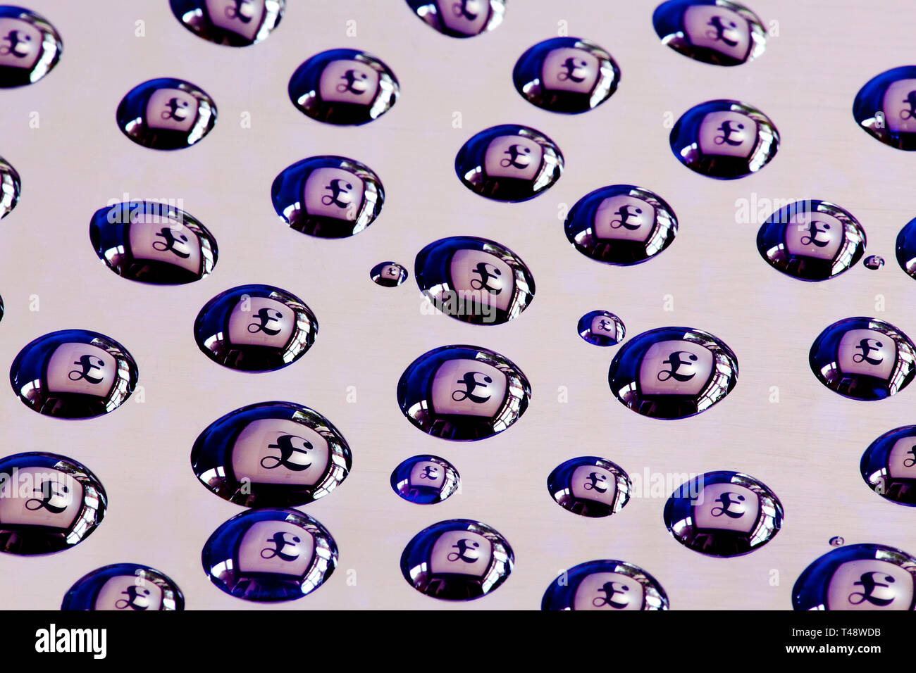Water drops on acrylic with pound sterling symbols reflected in each drop. Stock Photo