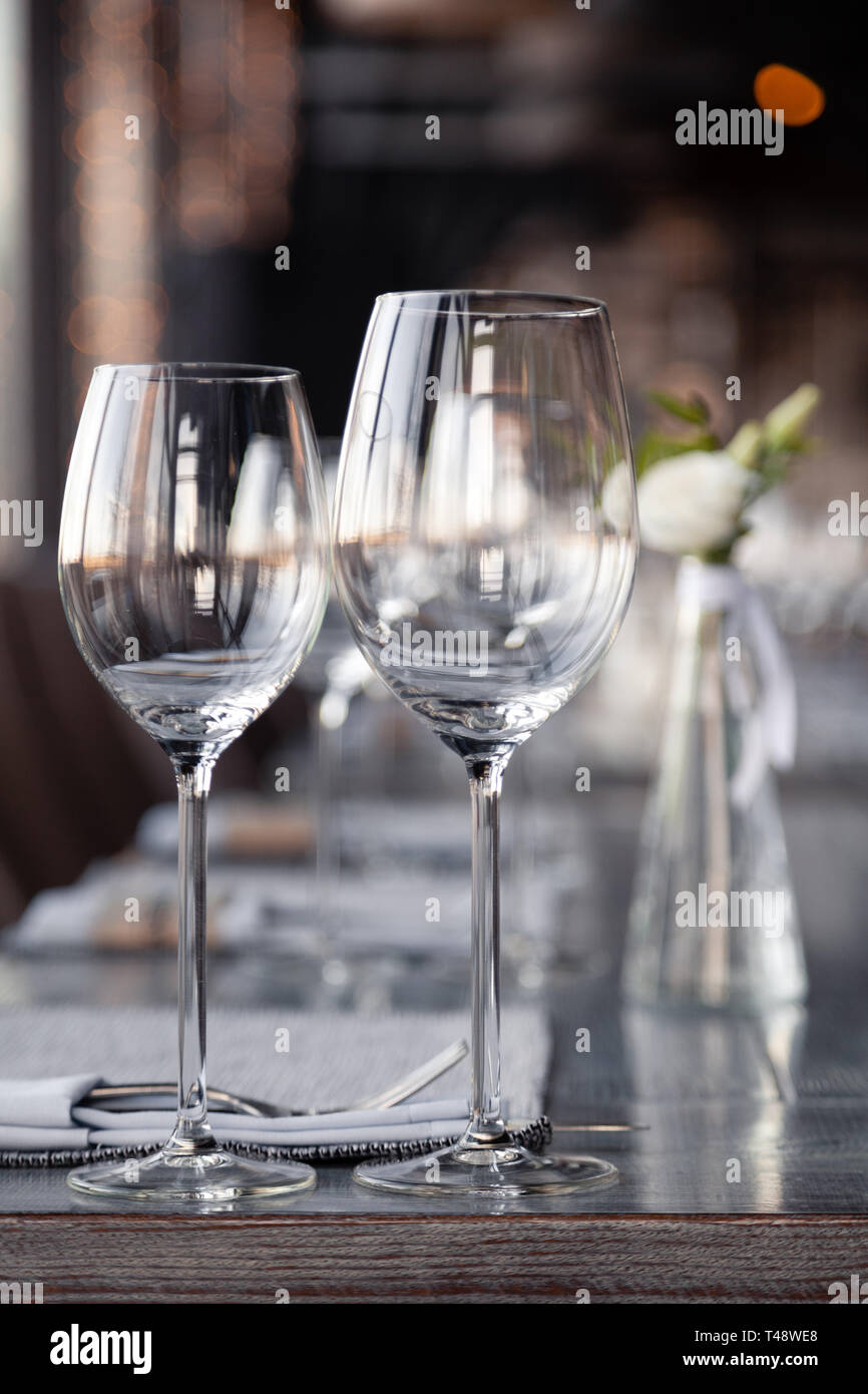 Modern restaurant setting, glass vase with bouquet flowers on table in