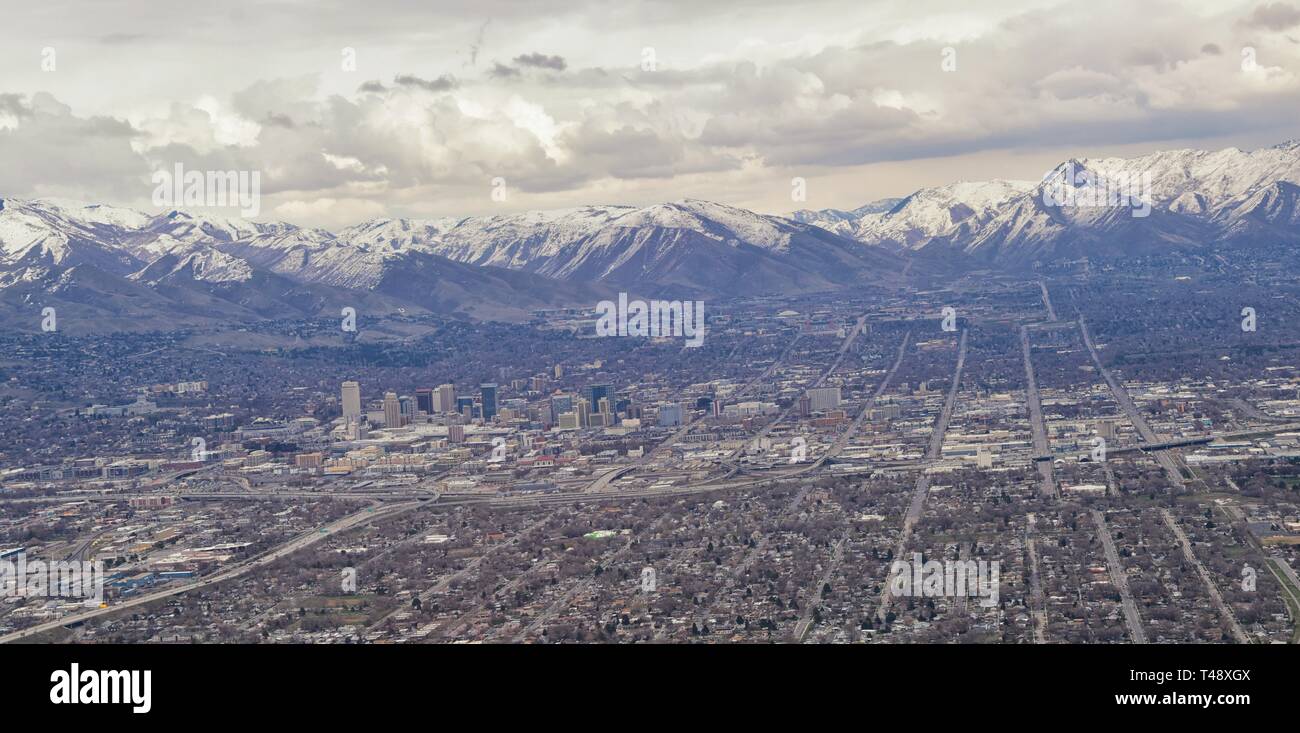 Downtown Salt Lake City Panoramic view of Wasatch Front Rocky Mountains from airplane in early spring winter with melting snow and cloudscape. Utah, U Stock Photo