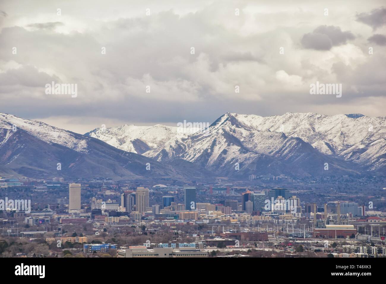 Downtown Salt Lake City Panoramic view of Wasatch Front Rocky Mountains from airplane in early spring winter with melting snow and cloudscape. Utah, U Stock Photo