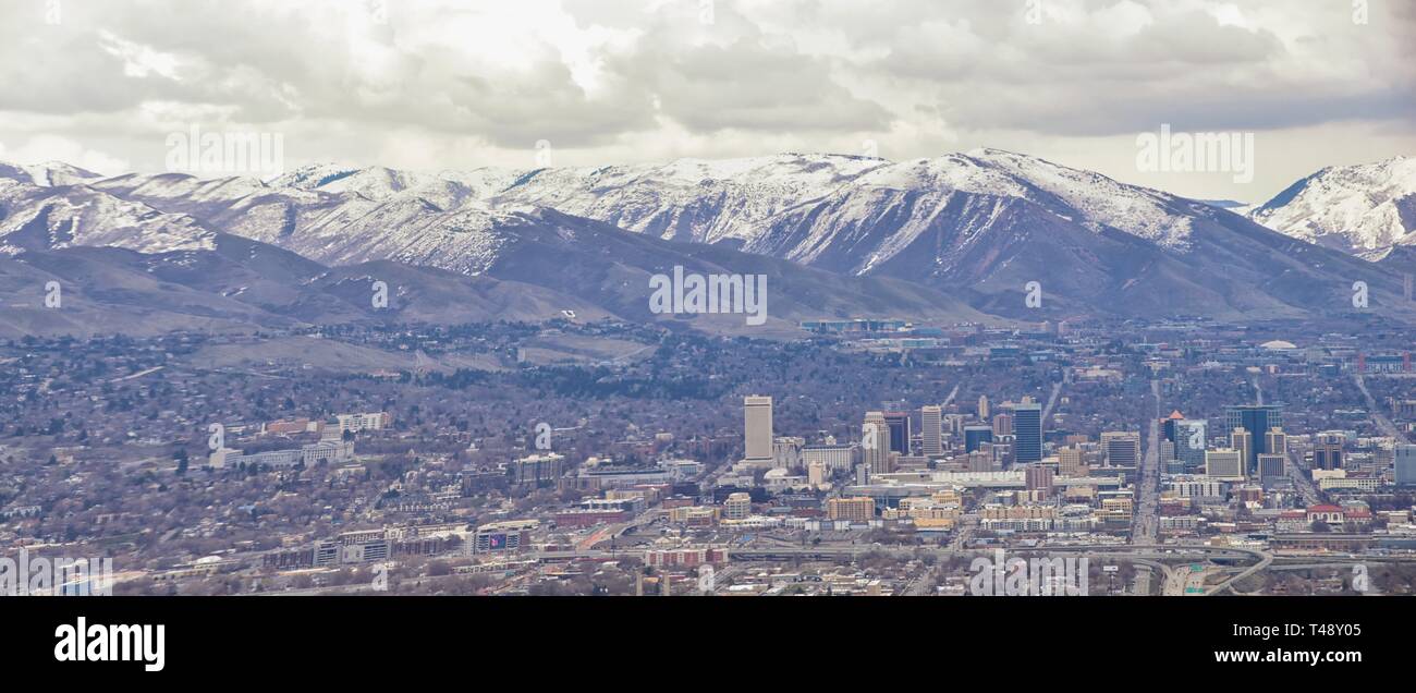 Downtown Salt Lake City Panoramic view of Wasatch Front Rocky Mountains from airplane in early spring winter with melting snow and cloudscape. Utah, U Stock Photo
