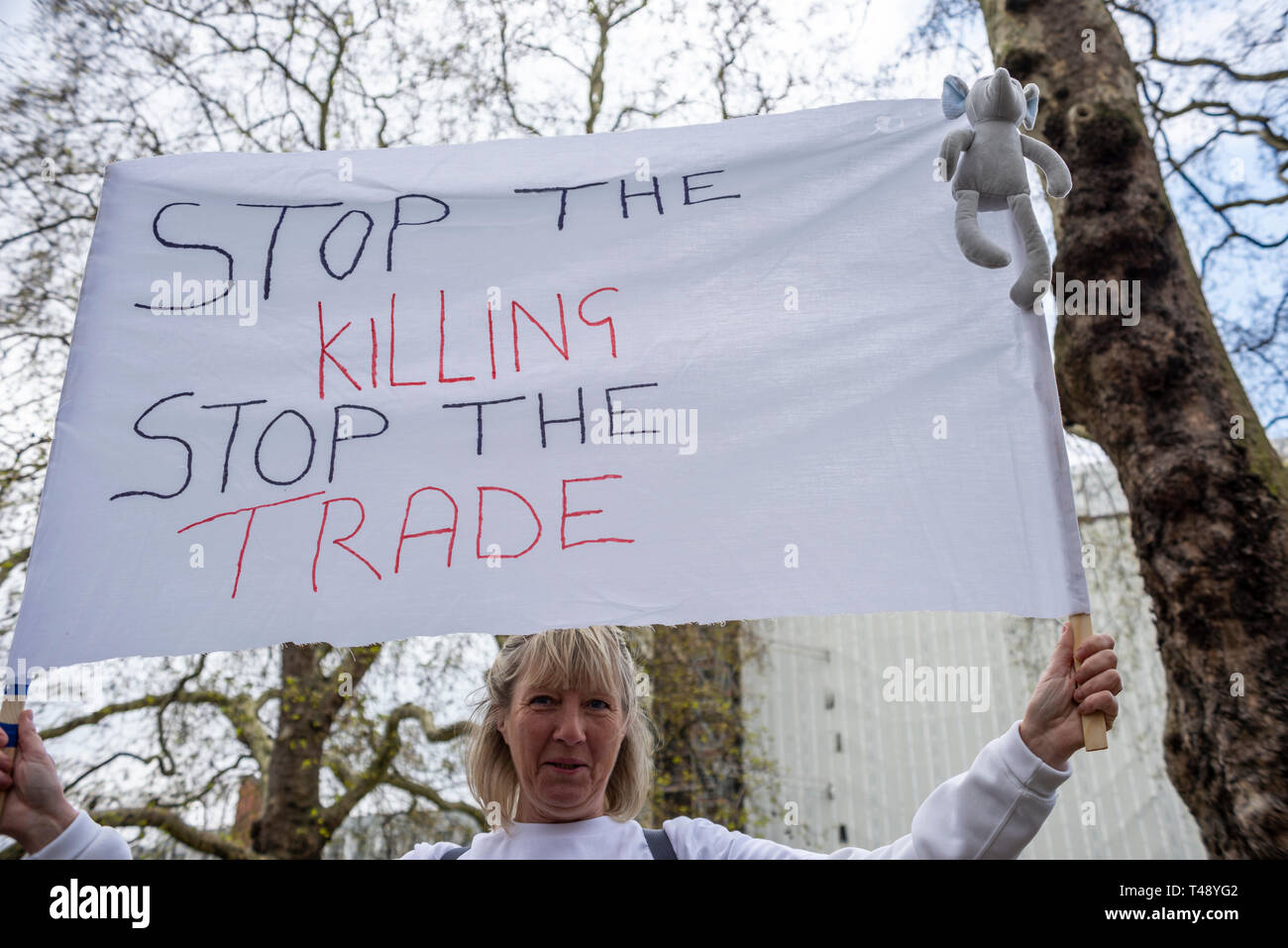 Protester at a stop trophy hunting and ivory trade protest rally, London, UK. Banner requesting stop the killing, stop the trade. Female Stock Photo