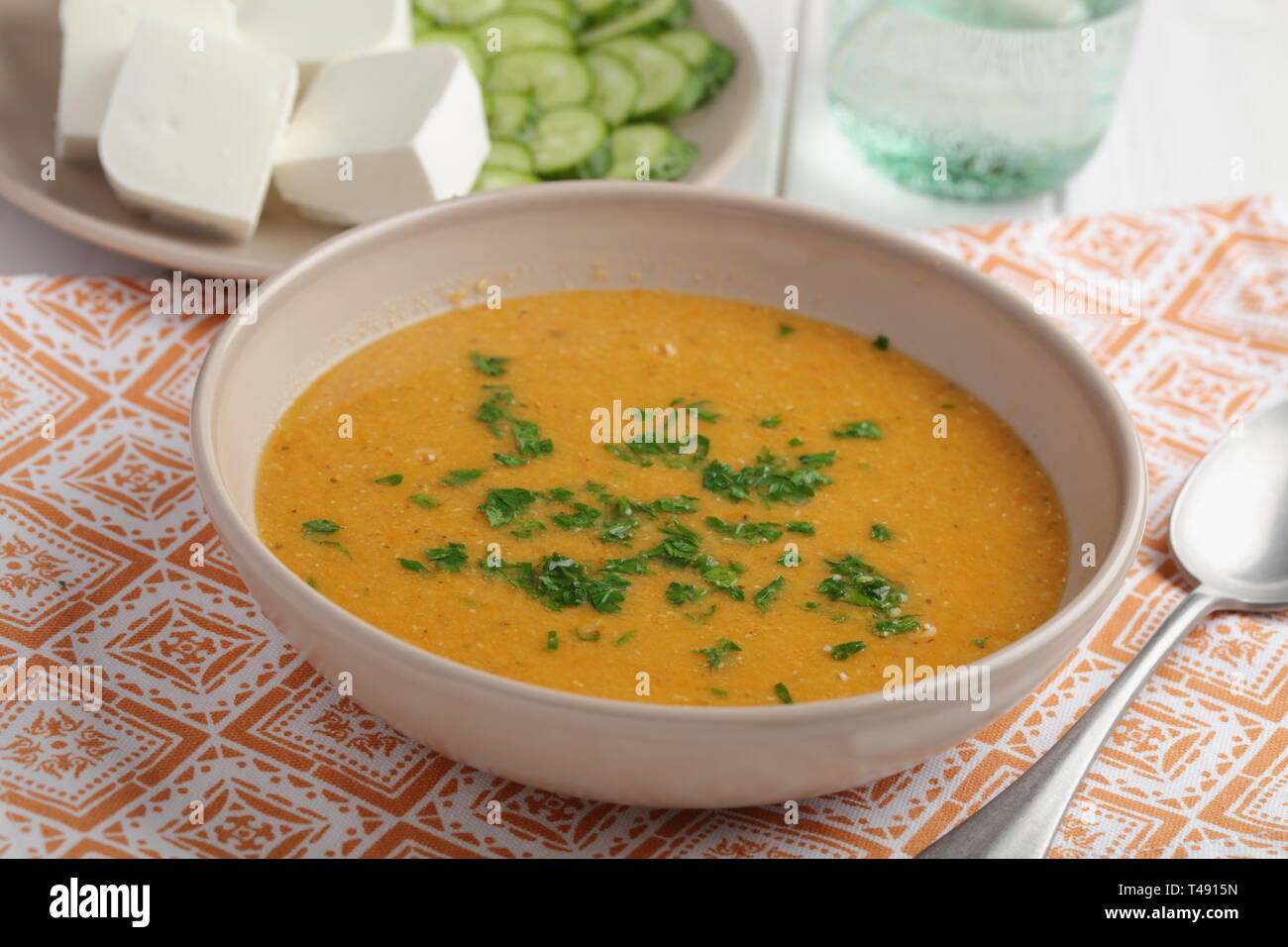 Mercimek corba, traditional Turkish lentil soup served with cheese, cucumbers, and parsley Stock Photo