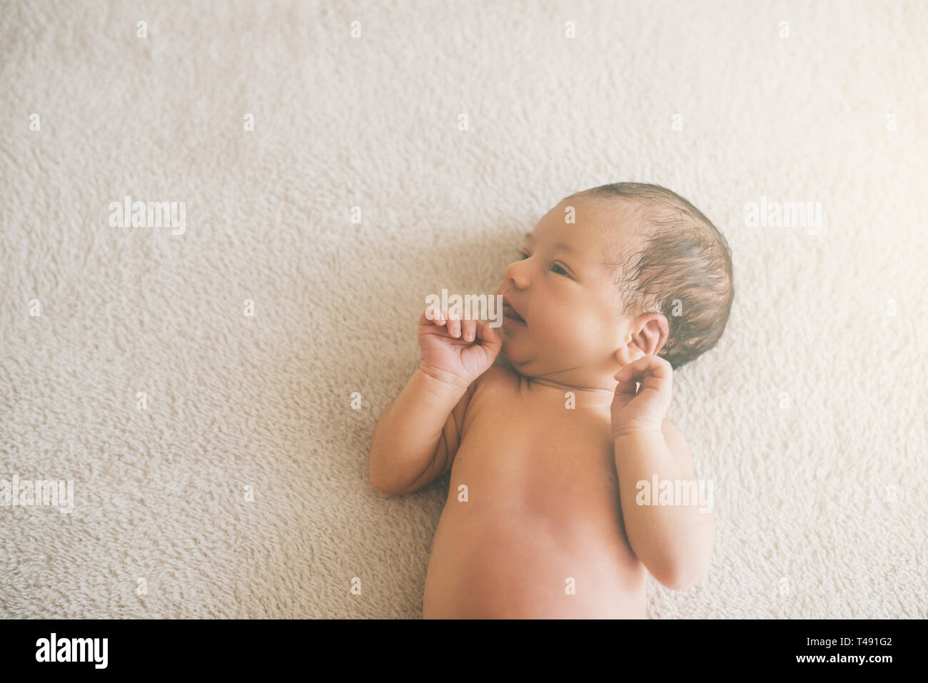 one week old newborn baby girl sleeping on a grey blanket Stock Photo