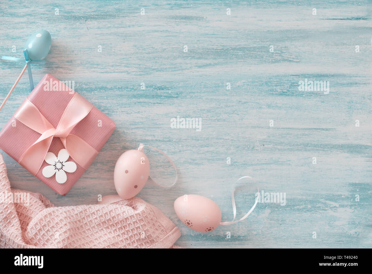 Easter flat lay in pastel colors with copy-space. Wrapped gift box, decorative flowers and Easter eggs. Stock Photo