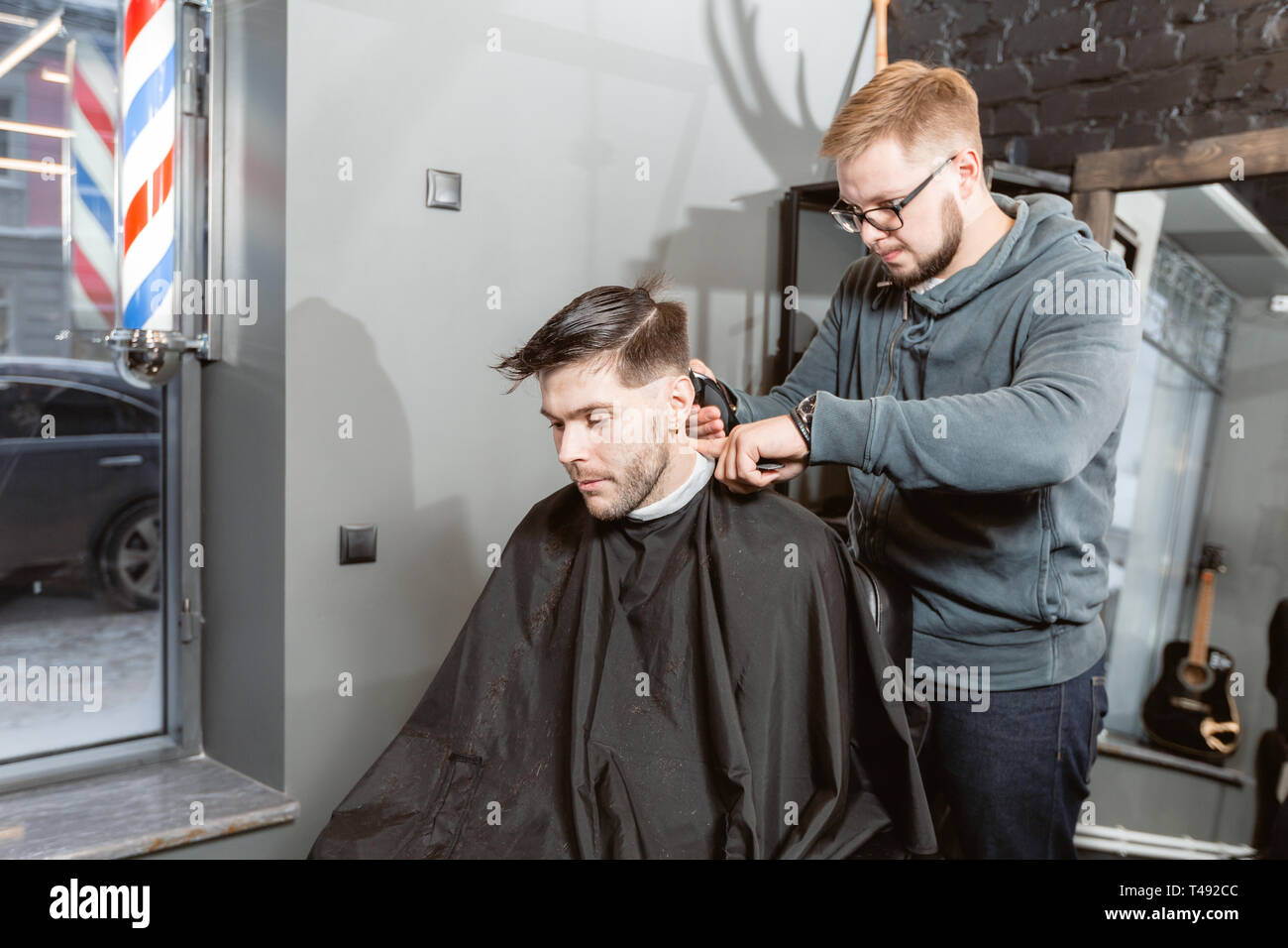 Master cuts hair and beard of men in the barbershop, hairdresser makes ...