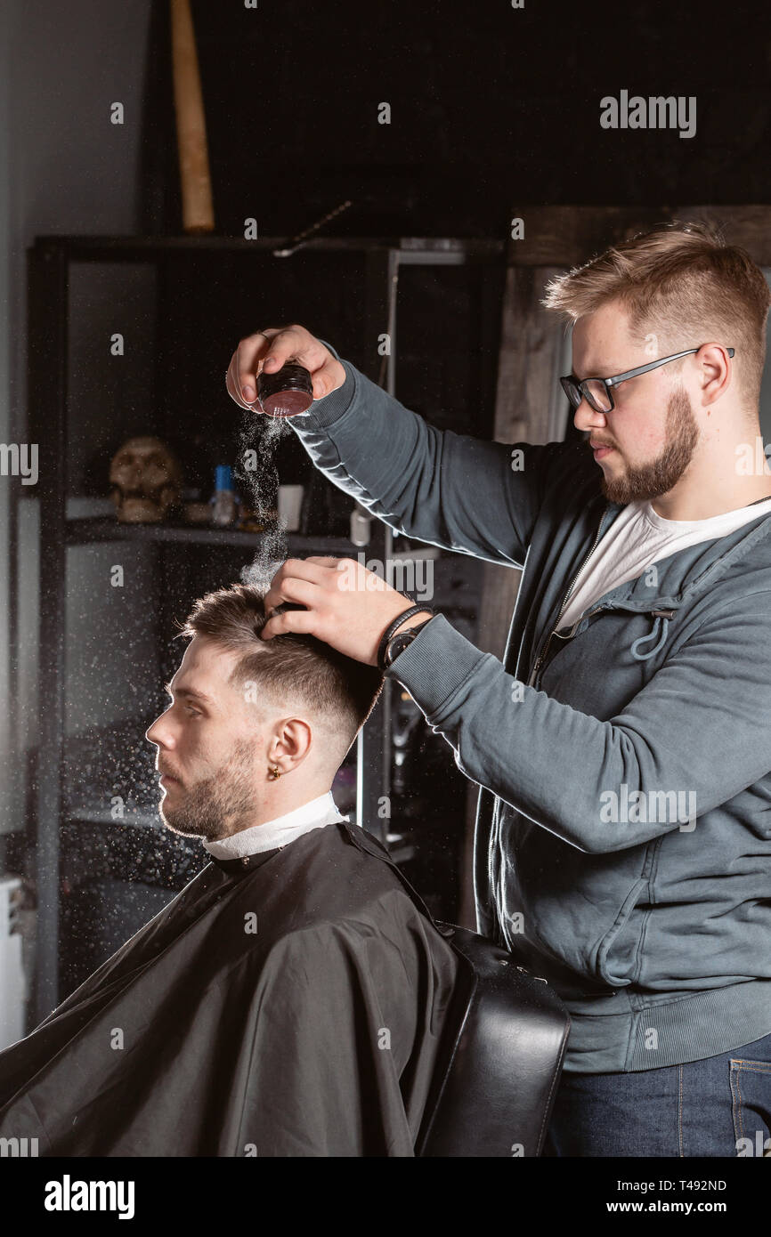 Master barber pours out styling powder to fix hair. hairdresser makes  hairstyle for a young man Stock Photo - Alamy