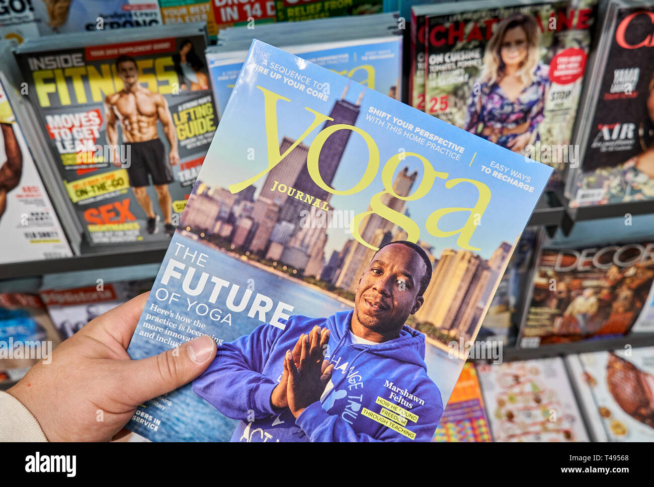 MONTREAL, CANADA - OCTOBER 9, 2018: Yoga Journal with Marshawn Feltus in a hand over a stack of magazines. Yoga Journal is an American media company t Stock Photo