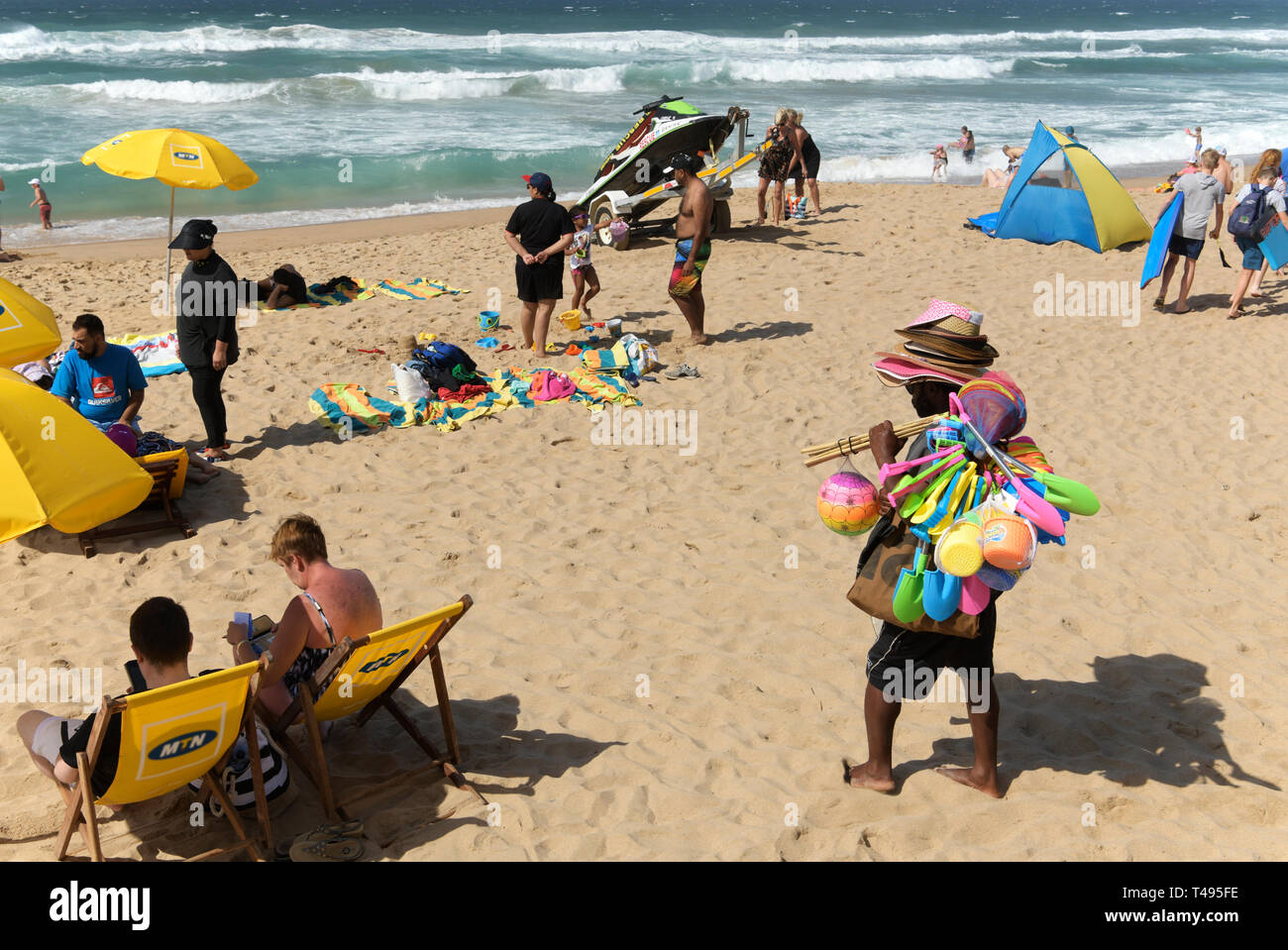 Durban, KwaZuluNatal, South Africa, street vendor walking on beach selling colourful toys to